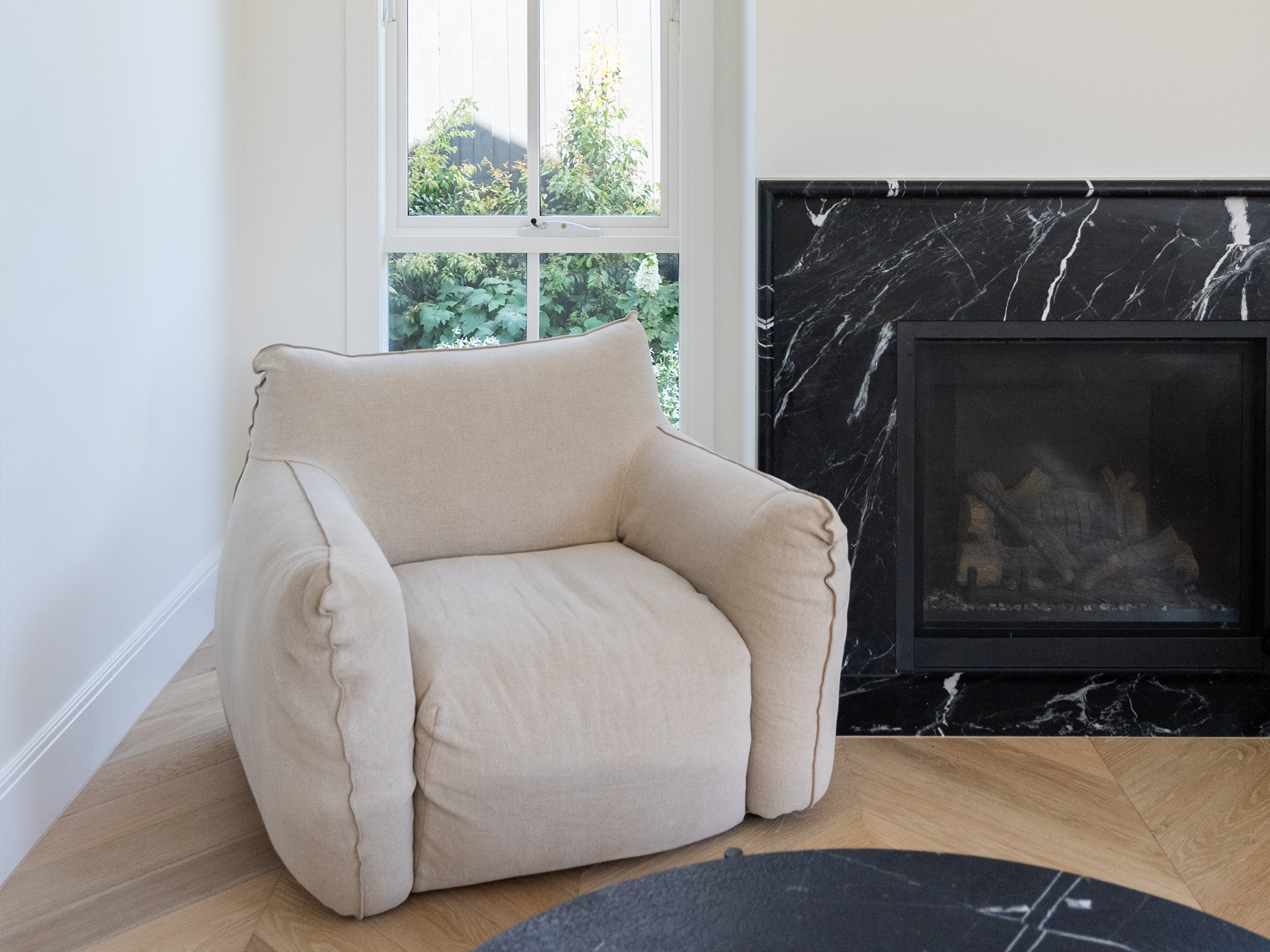 Living room renovation Melbourne with armchair by window and marble fireplace feature