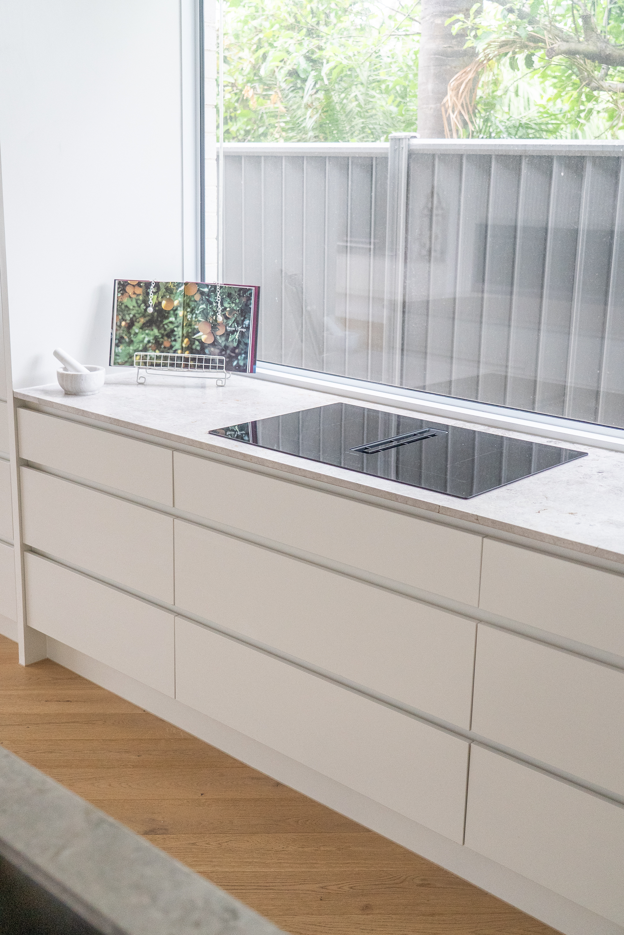 Kitchen renovation Melbourne with minimalist cabinetry, built-in cooktop, and large window design