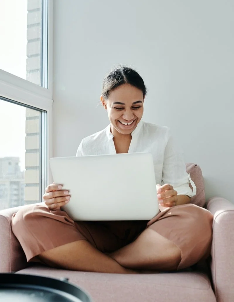 Midlife woman sitting comfortably with a laptop, representing support and guidance for gut health during perimenopause