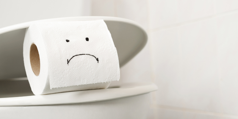 Roll of toilet paper with a sad face sitting on a toilet, symbolizing digestive discomfort and gut health struggles in midlife women.
