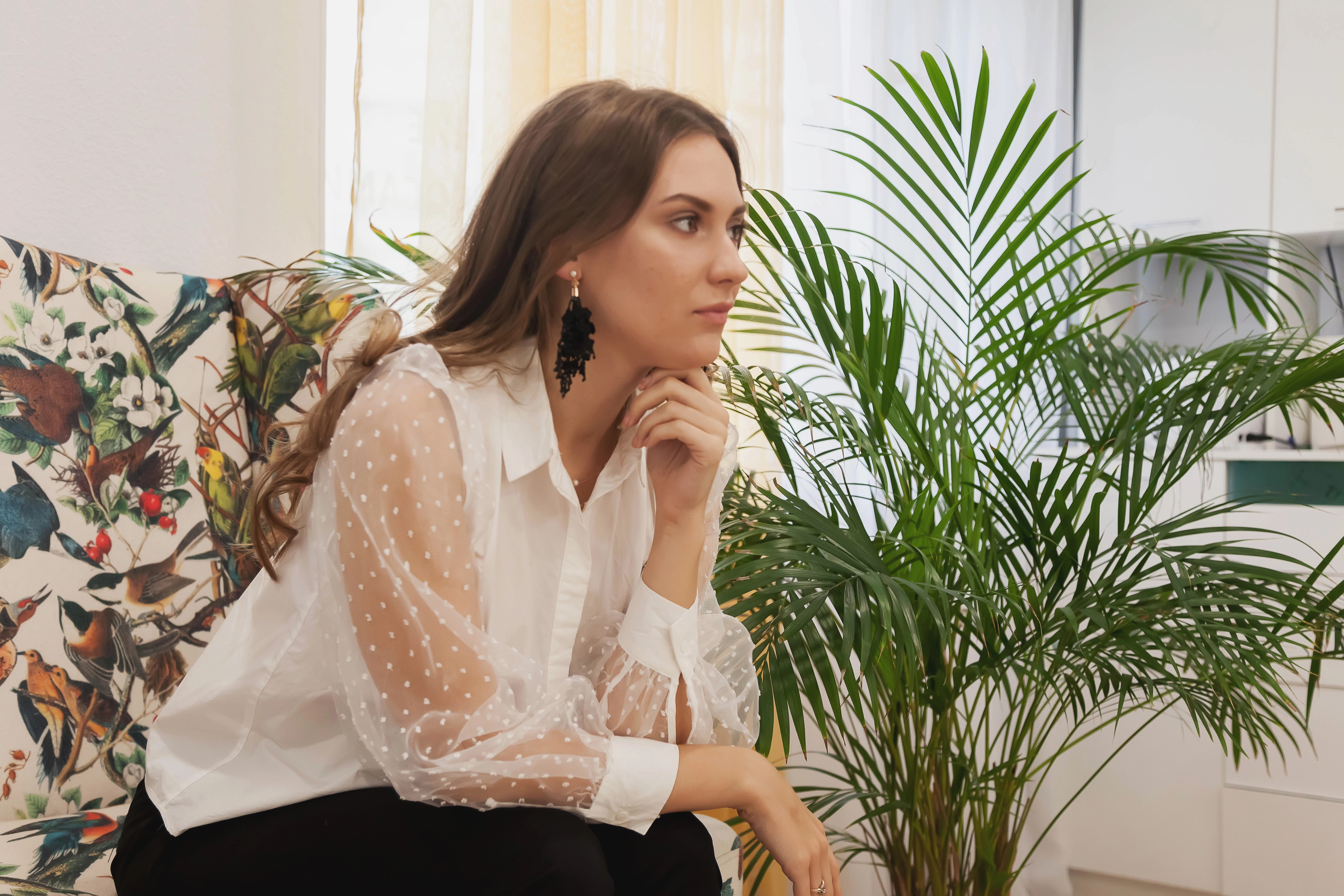 Woman sitting quietly in a bright room, appearing thoughtful while considering her health and wellness journey.