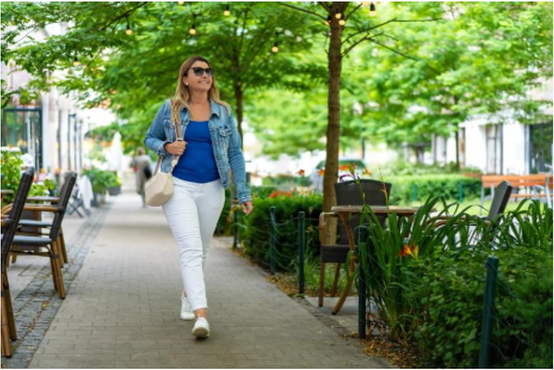 Woman walking confidently outdoors in a green urban park, representing improved wellbeing and freedom from digestive symptoms