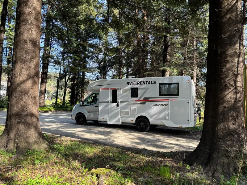 RV Rentals motorhome beneath trees at a woodland stop