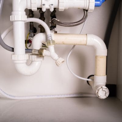 View of a complex under-sink pipe setup with multiple connections