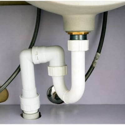 Under-sink white PVC pipes installed with a P-trap for efficient drainage