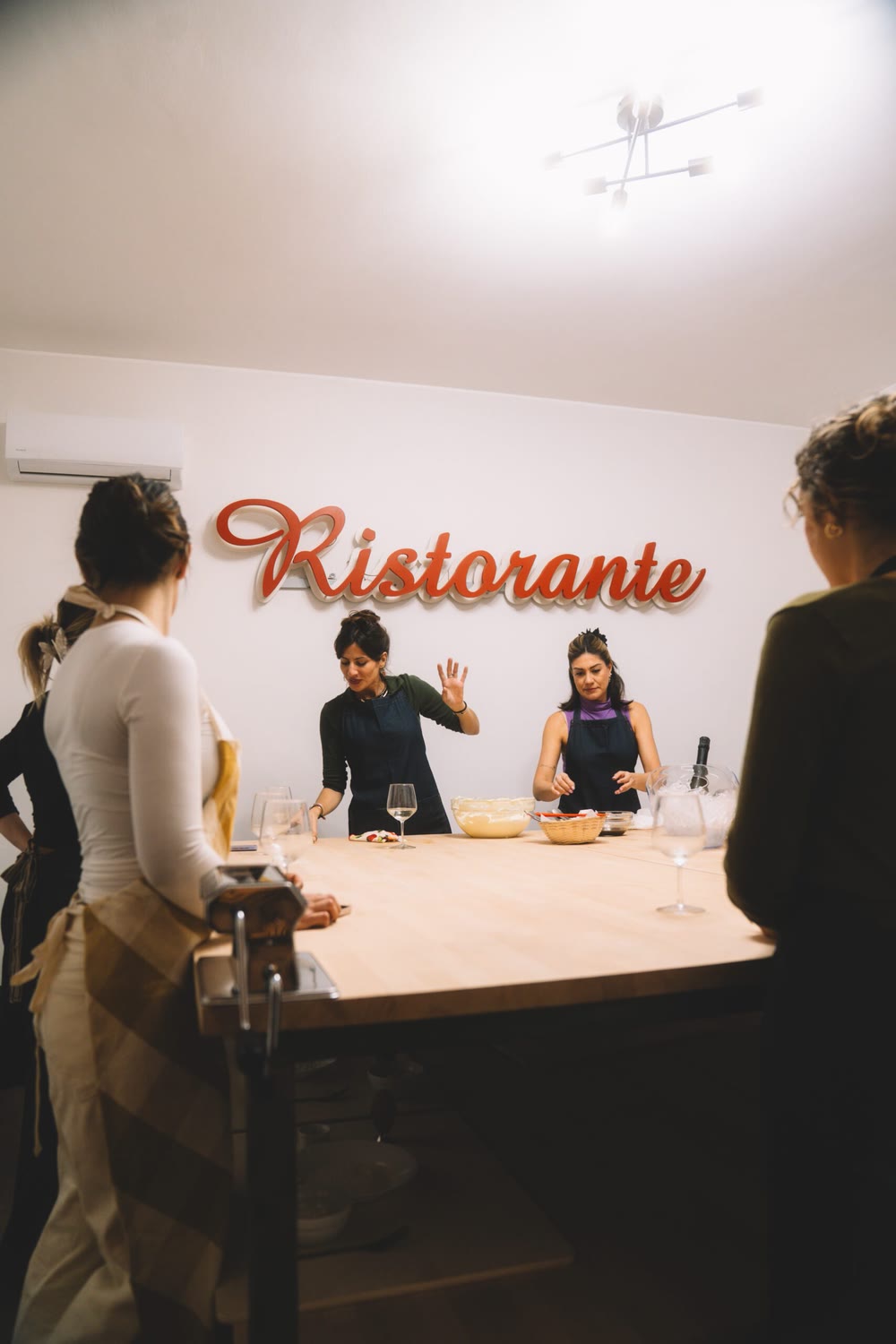 Two Roman cooks leading the cooking class under a red Ristorante sign