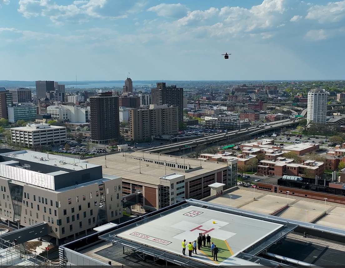 Drone approaching a rooftop hospital helipad in an urban medical campus