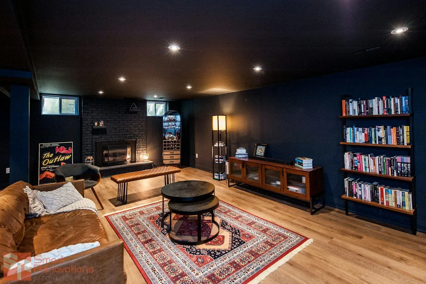 A finished lower-level living room with bookshelves, a fireplace and a rug