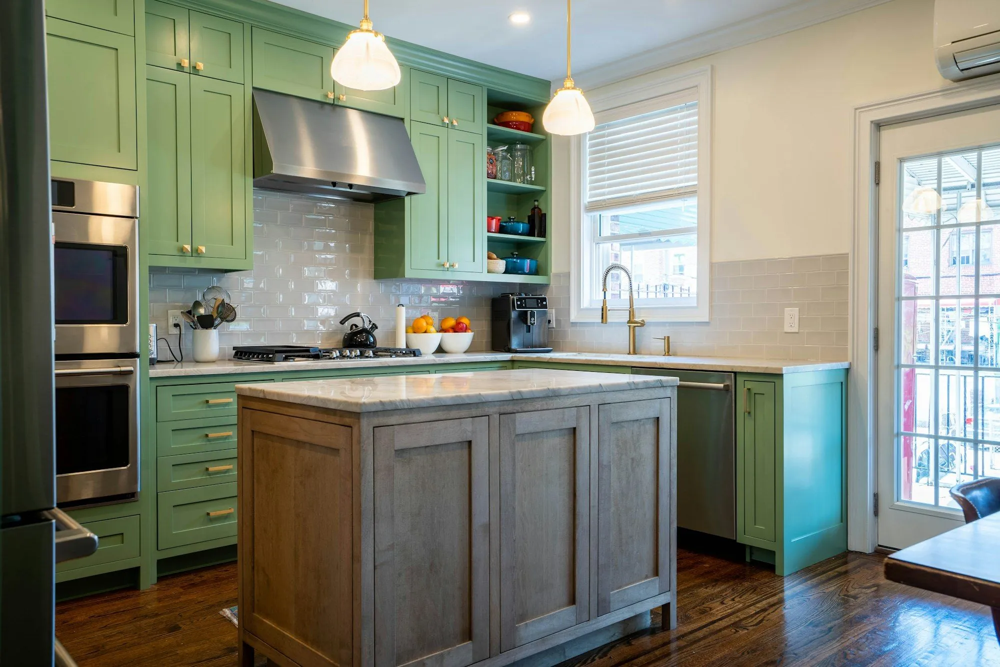 A remodeled kitchen with painted green cabinets, a wood island and white counters