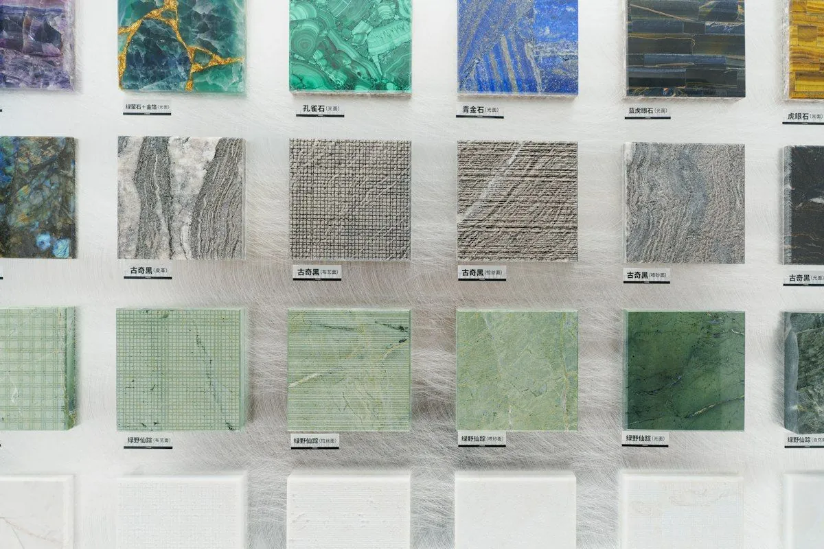 A wall of stone and tile samples in greens and greys