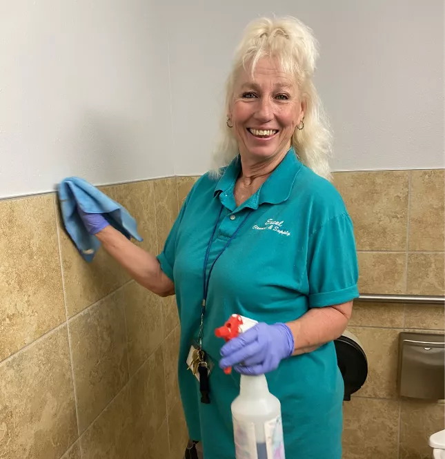 Smiling Excel Cleaning & Supply team member holding cleaning supplies in a commercial facility