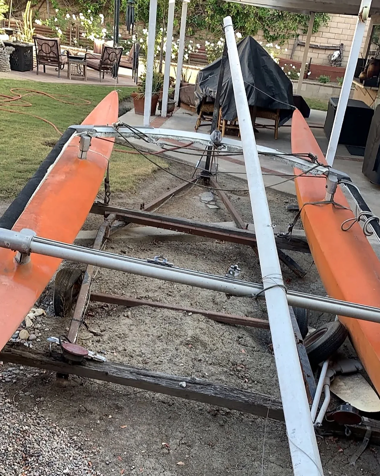 An old catamaran sitting on its trailer.