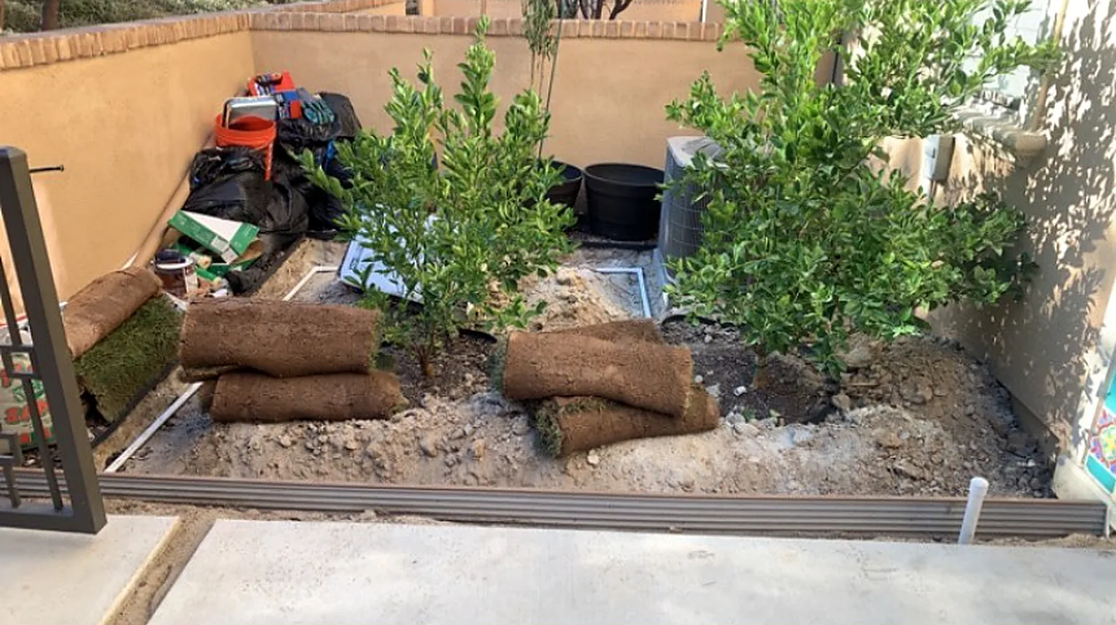 A courtyard with rolls of sod, soil and bagged yard debris.