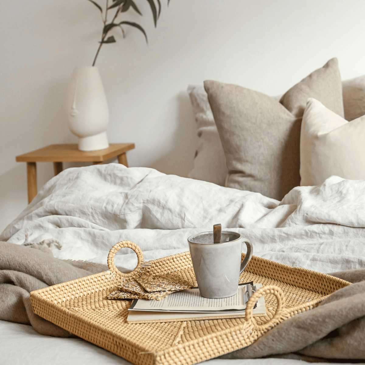 Professionally staged bedroom with neutral bedding, textured pillows, a bedside table, and cozy styling designed to create buyer appeal and enhance real estate listing photos.