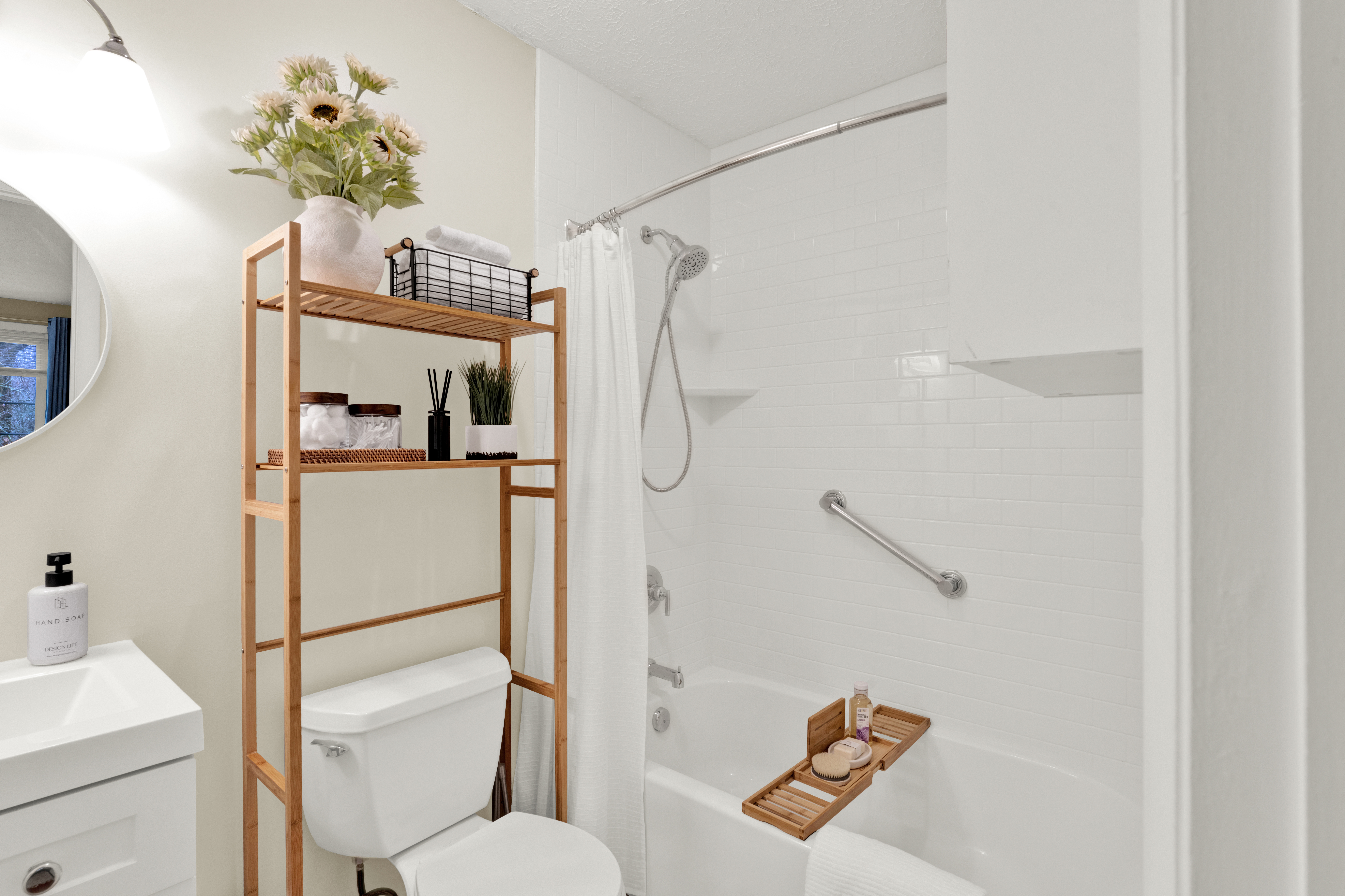 Professionally staged bathroom with neutral decor, fresh flowers, organized shelving, white subway tile shower, and spa-inspired styling designed to enhance buyer appeal.