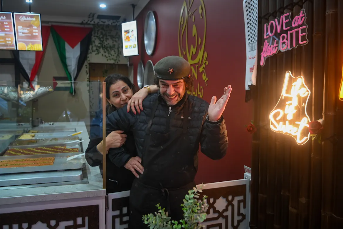 People standing around a shared knafeh tray at an event