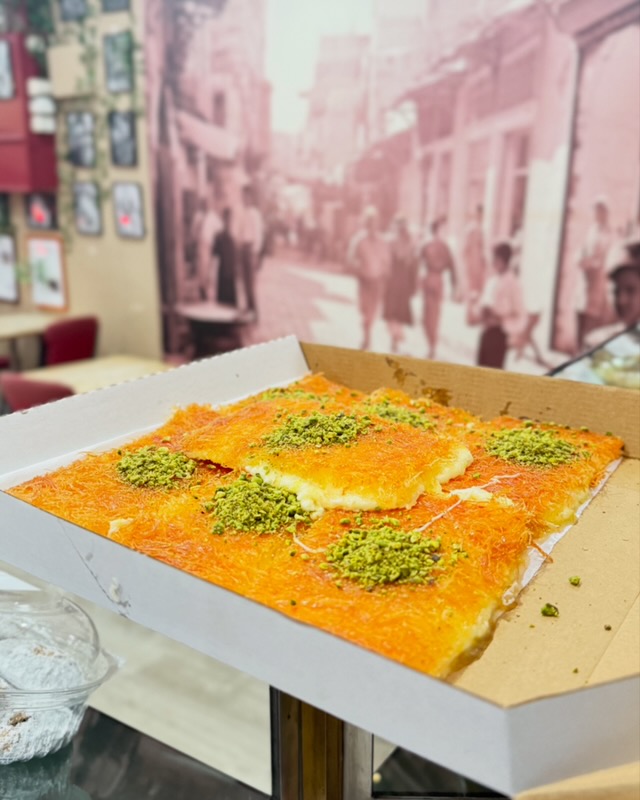 Close-up of freshly prepared knafeh being shared at a Melbourne event