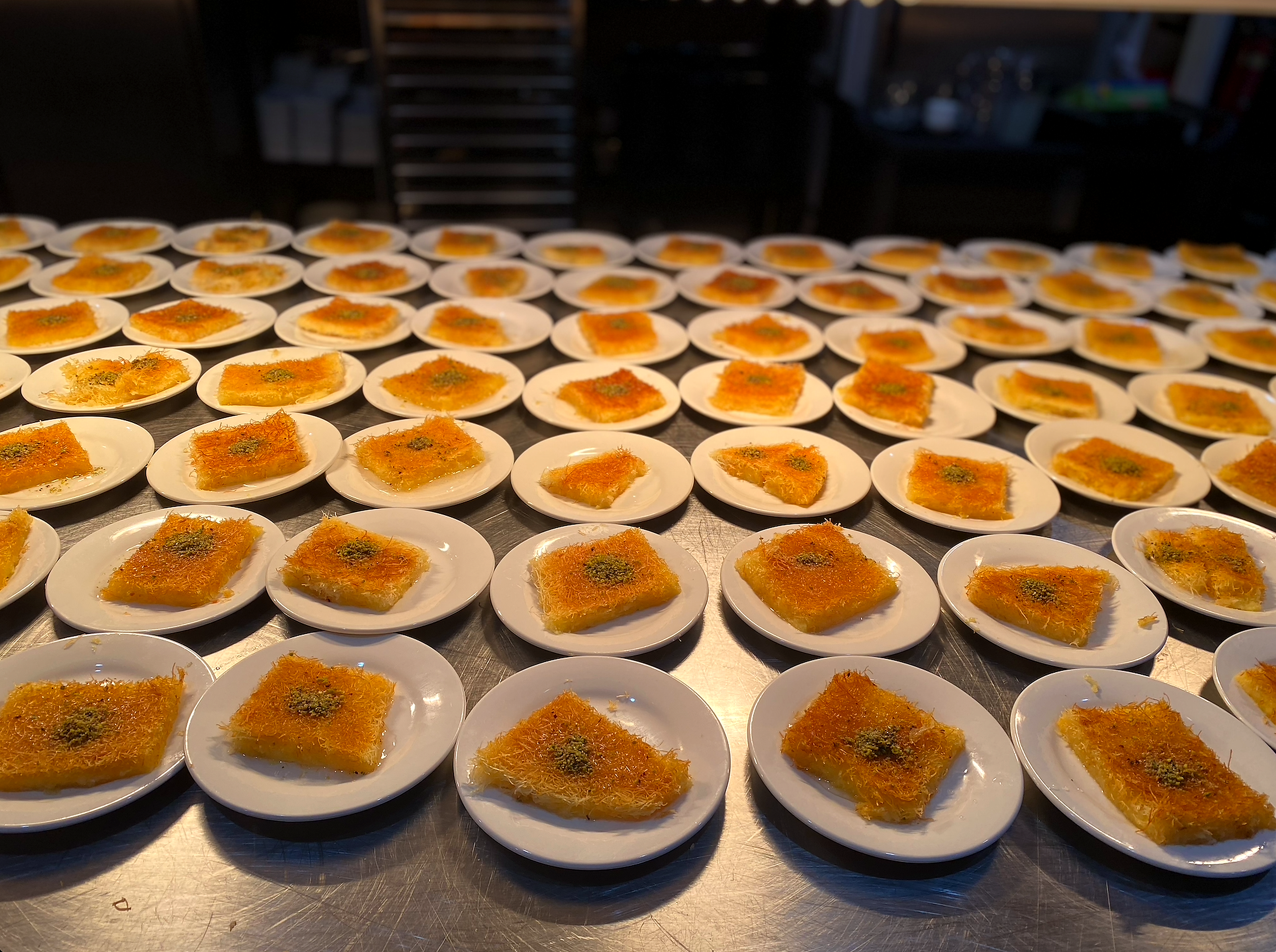 An elegant wedding dessert table featuring a golden knafeh tray
