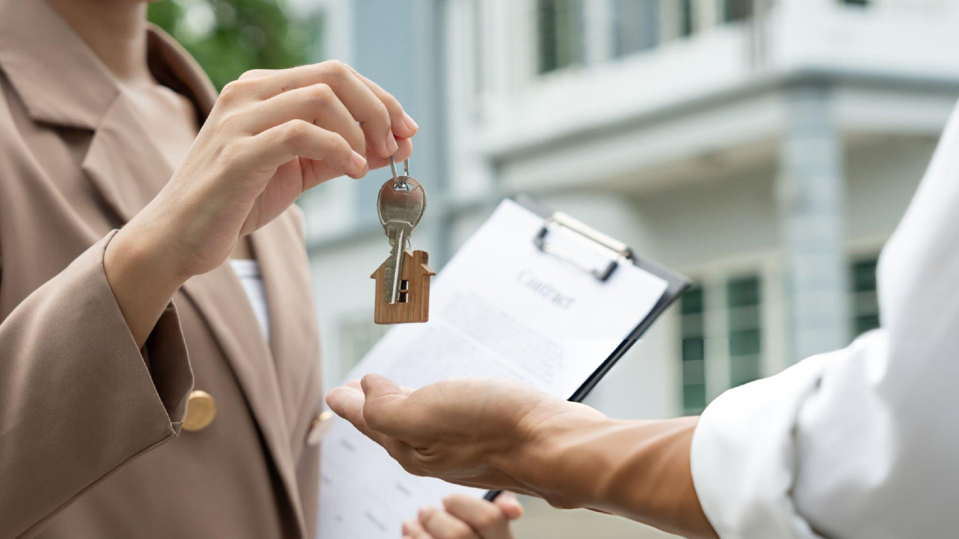 Real estate agent hands house keys to a client during a property transaction in modern office. Real estate agent hands house keys to a client during a property transaction in modern office.