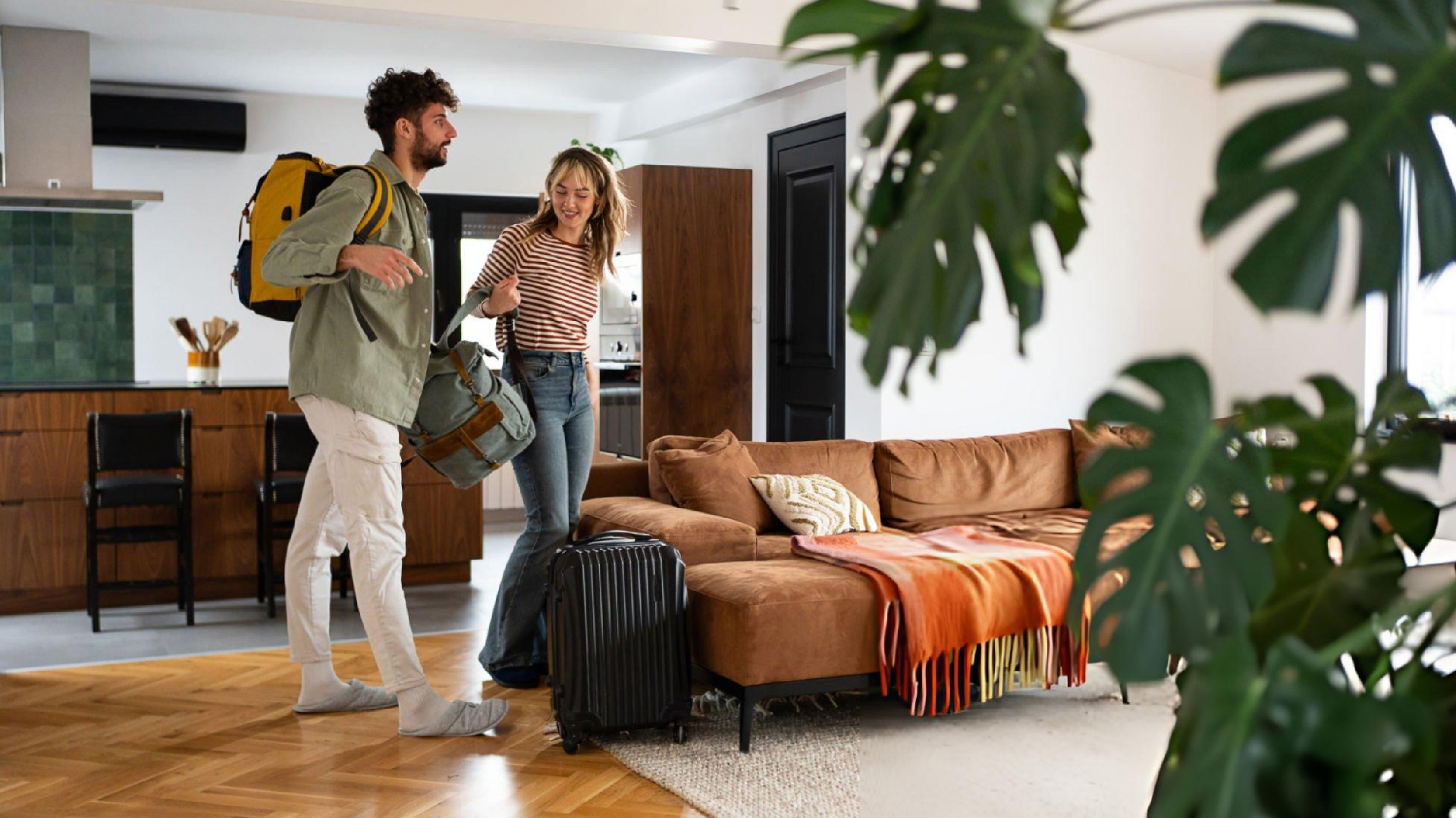 Couple arrives at a modern home with luggage and backpacks, ready for their stay together inside. Couple arrives at a modern home with luggage and backpacks, ready for their stay together inside.