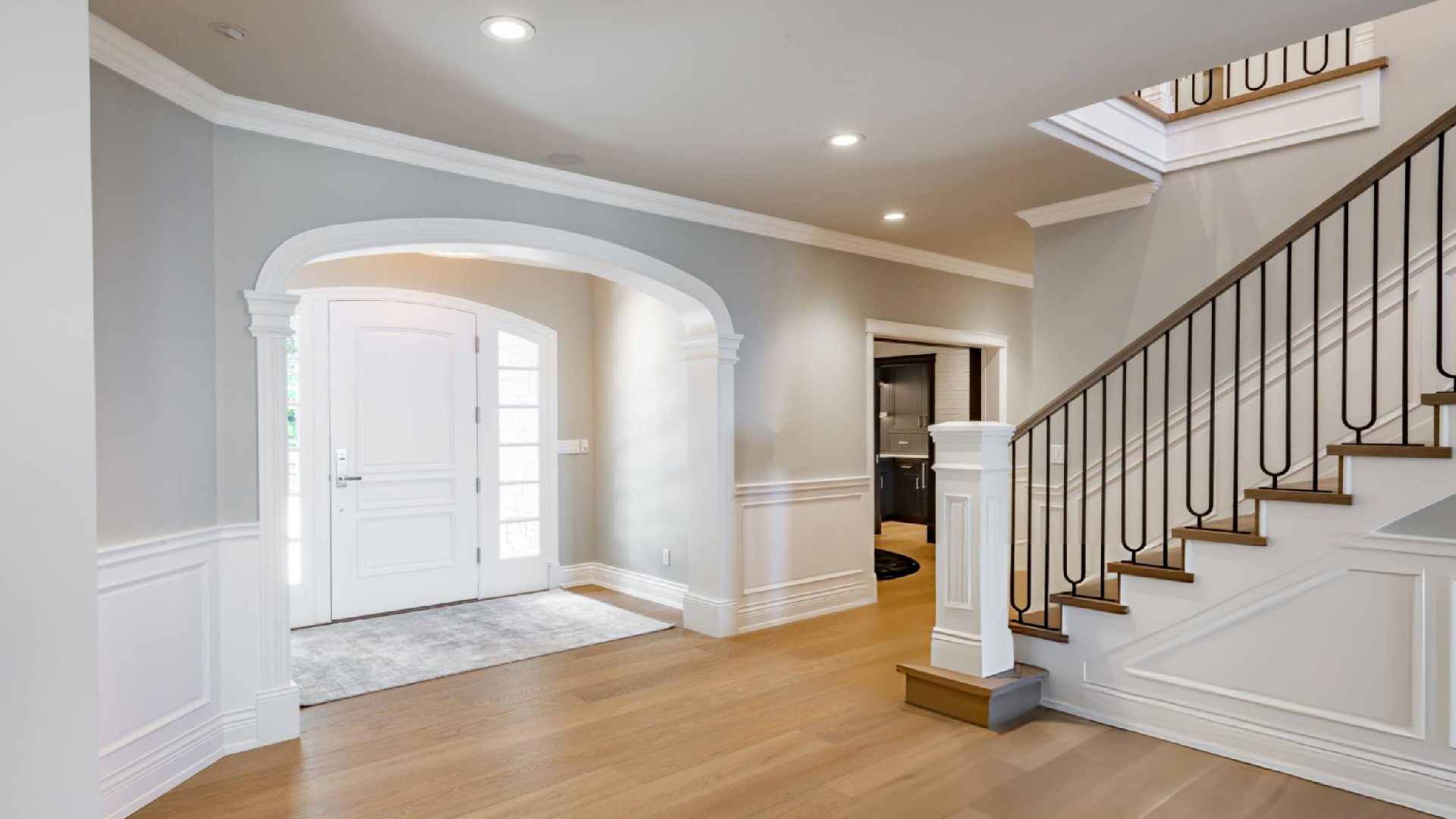 Bright modern home interior featuring a spacious entryway, staircase, hardwood floors, and elegant architectural details. Bright modern home interior featuring a spacious entryway, staircase, hardwood floors, and elegant architectural details.