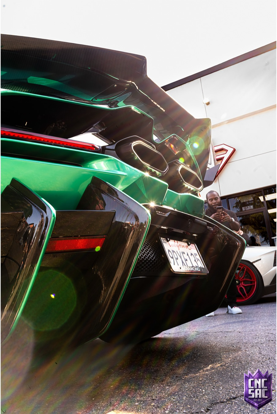 Green supercar with its rear hatch raised exhaust visible indoors