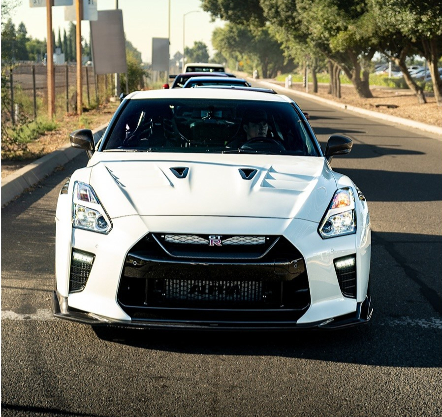 Front view of a white Nissan GT R on a tree lined street