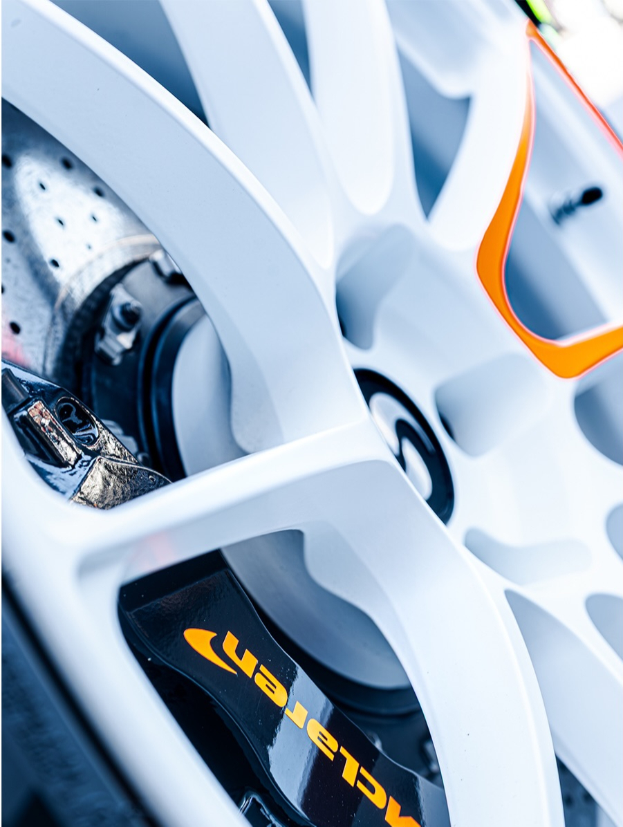 Close up of a white brake caliper and wheel with orange detailing