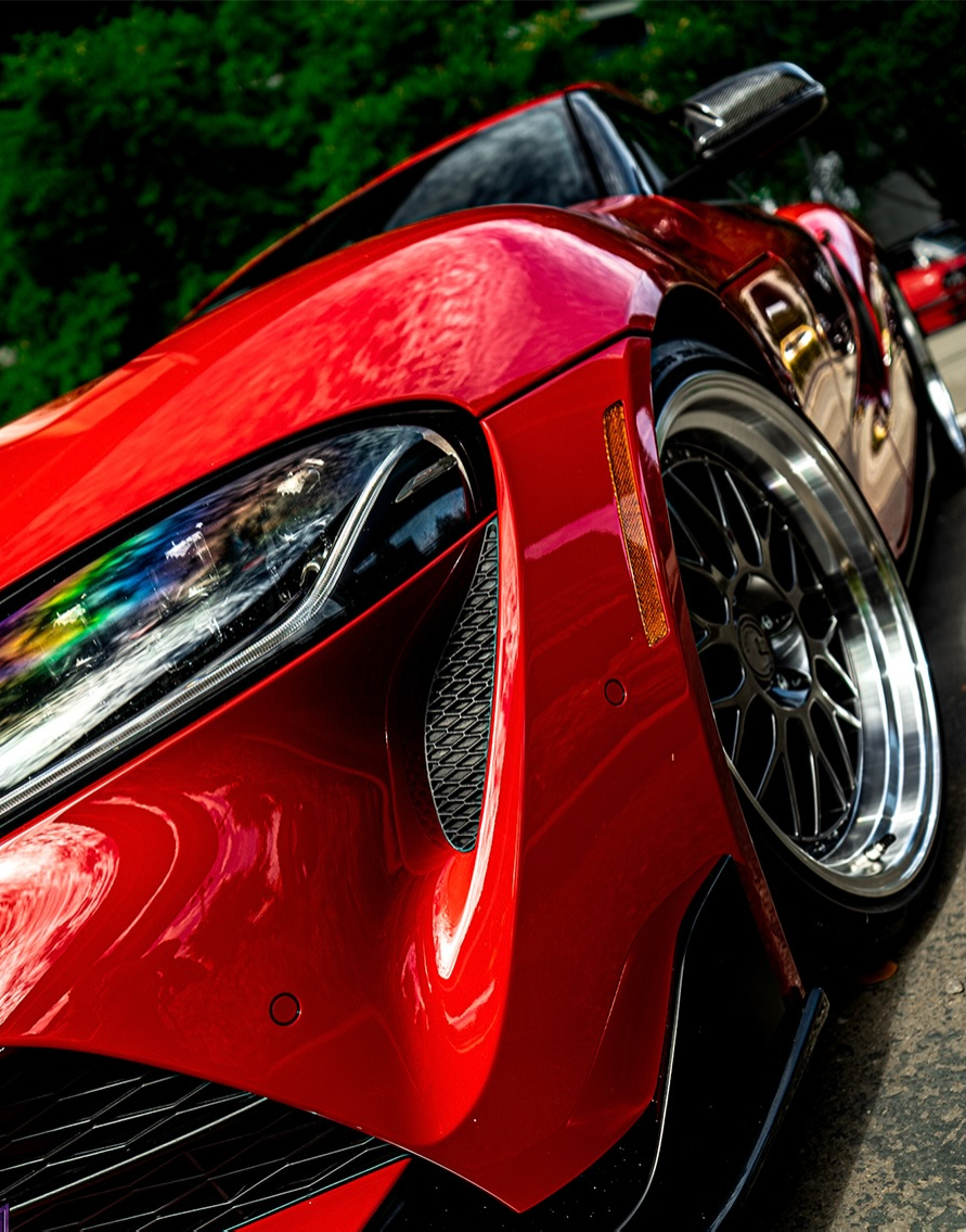 Close crop of a red coupes headlight and front fender