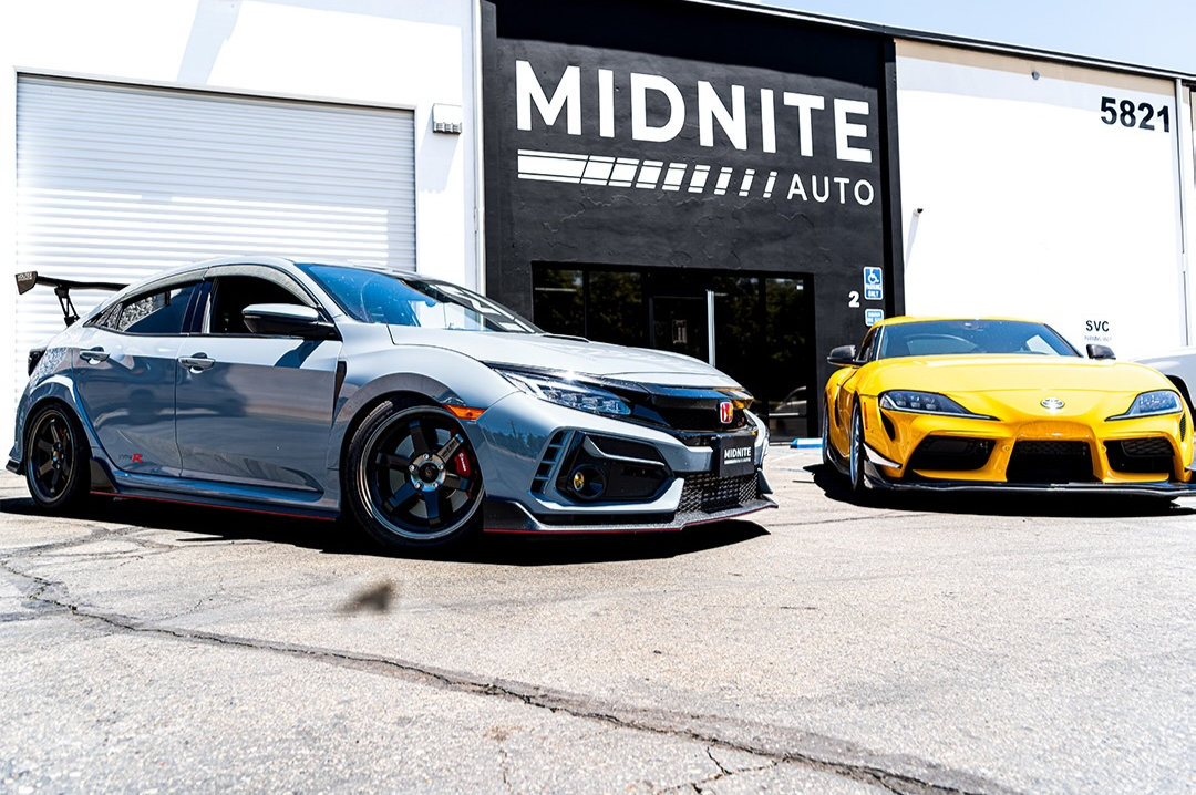 Grey Honda Civic Type R and a yellow Toyota Supra parked outside an auto shop