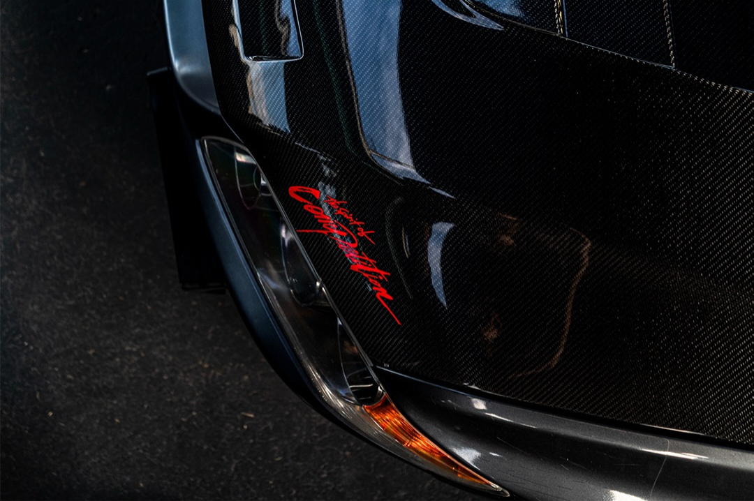 Low light detail of a carbon fibre rear wing with red script lettering