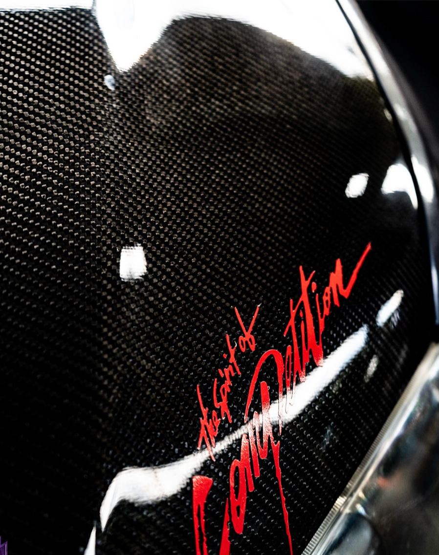 Close up of exposed carbon fibre weave with red script lettering across it