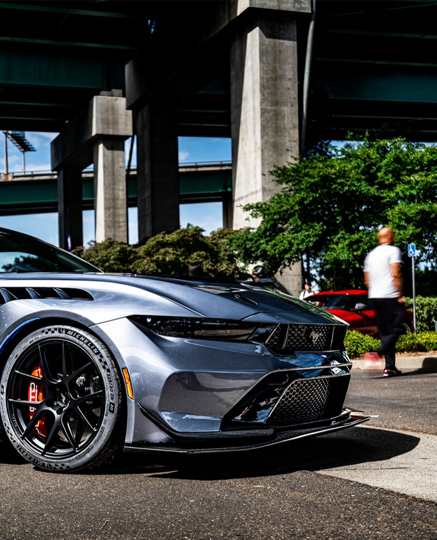 Front three quarter view of a grey modern Ford Mustang with a carbon front splitter