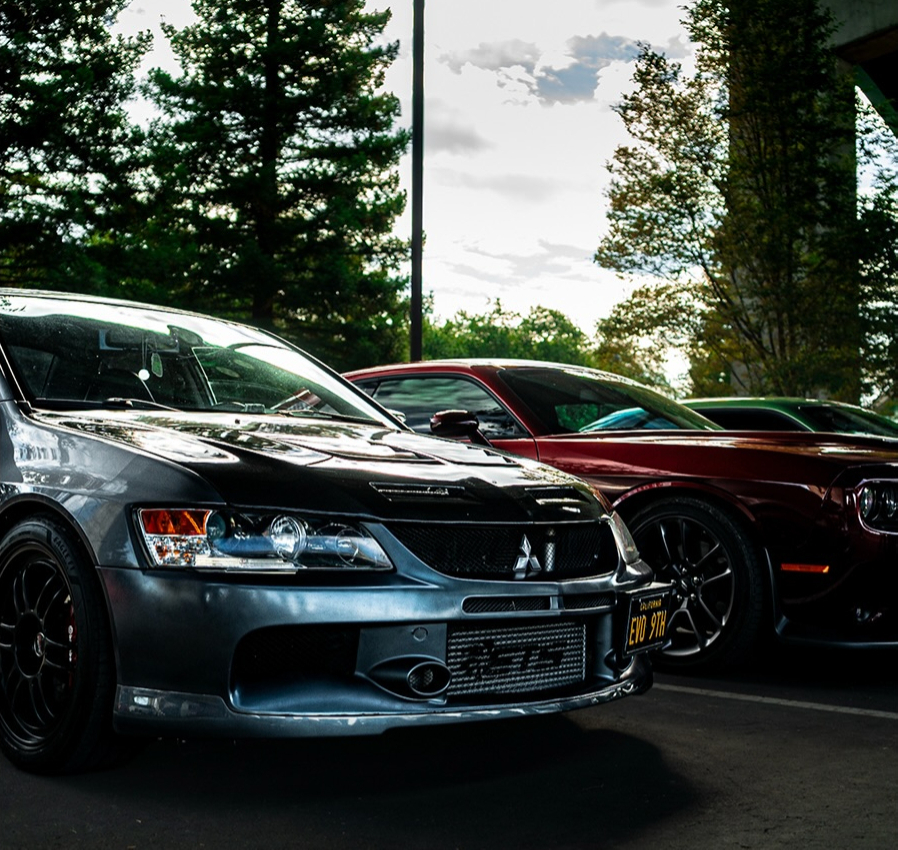 A row of cars parked nose in at an event with a grey Mitsubishi Lancer Evolution at the front