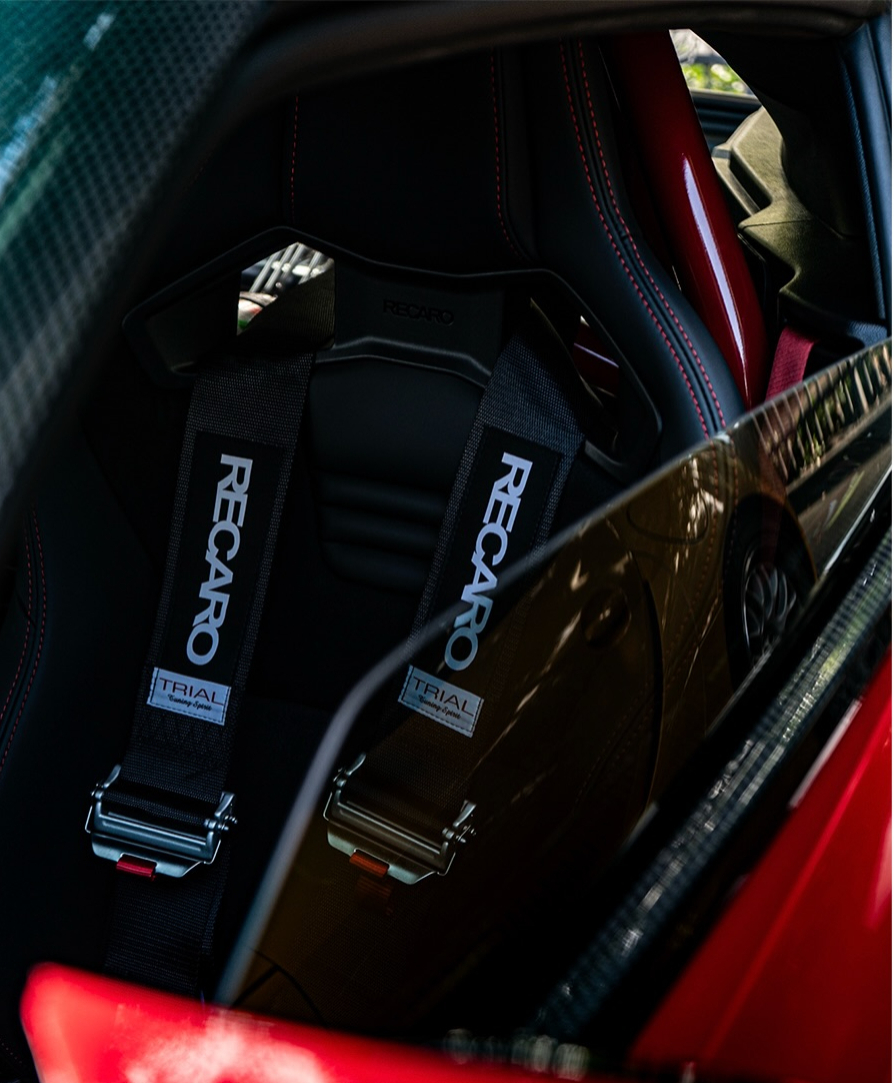 Black bucket seats with racing harnesses in a red cars interior