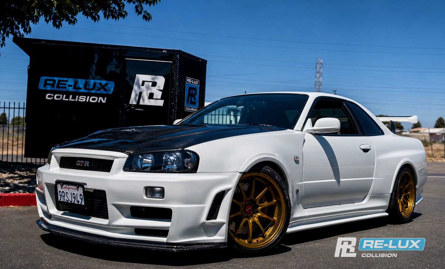 White Nissan Skyline GT-R parked in front of the Re-Lux Collision sign