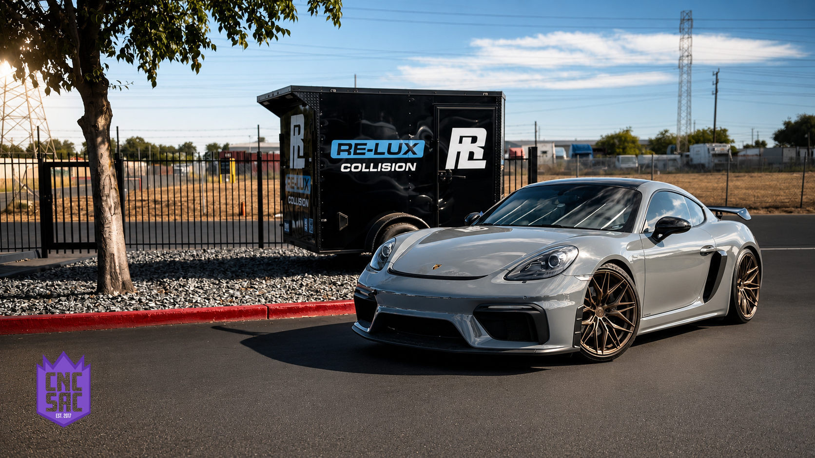 Grey Porsche 718 Cayman parked in front of the Re-Lux Collision sign