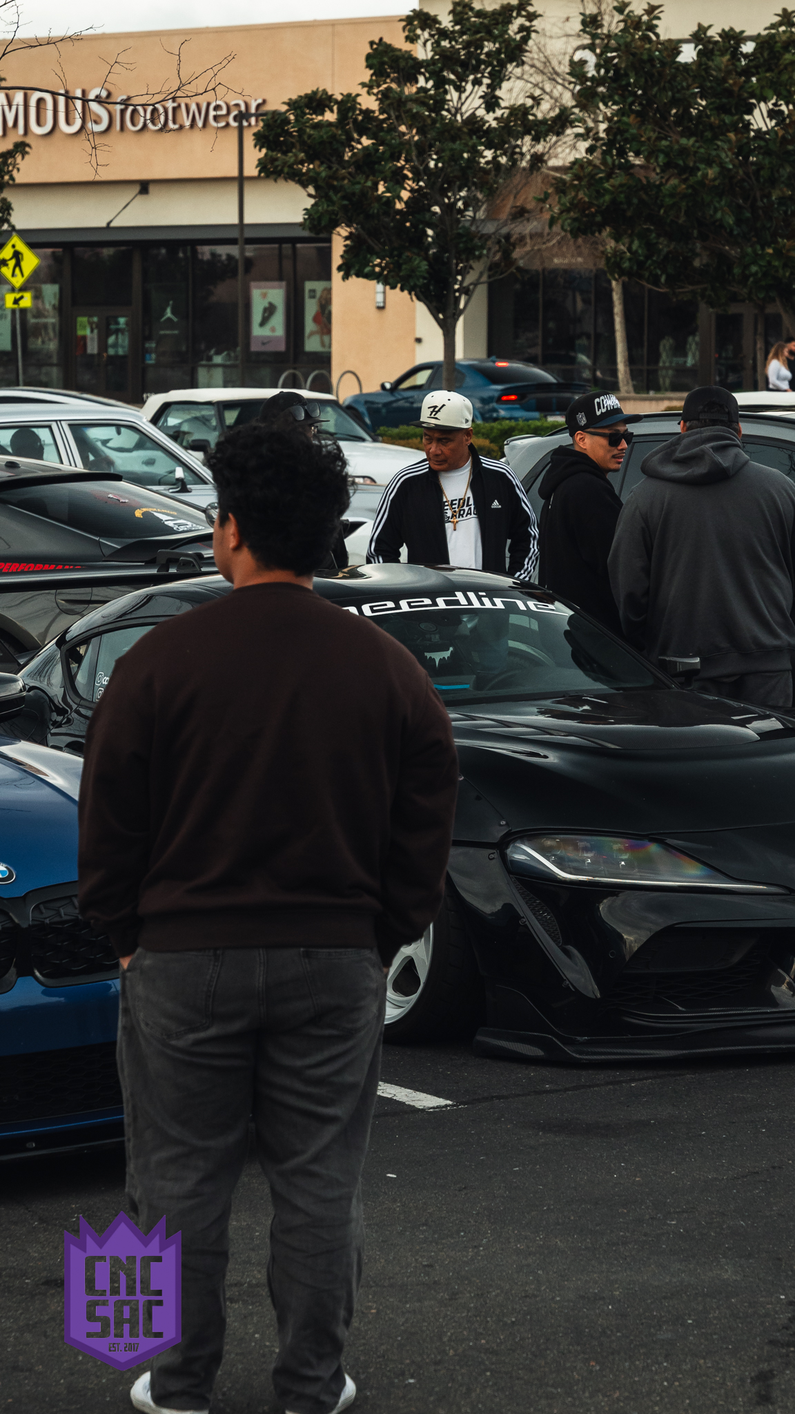 Attendees gathered around cars at a Cars and Coffee Sac event