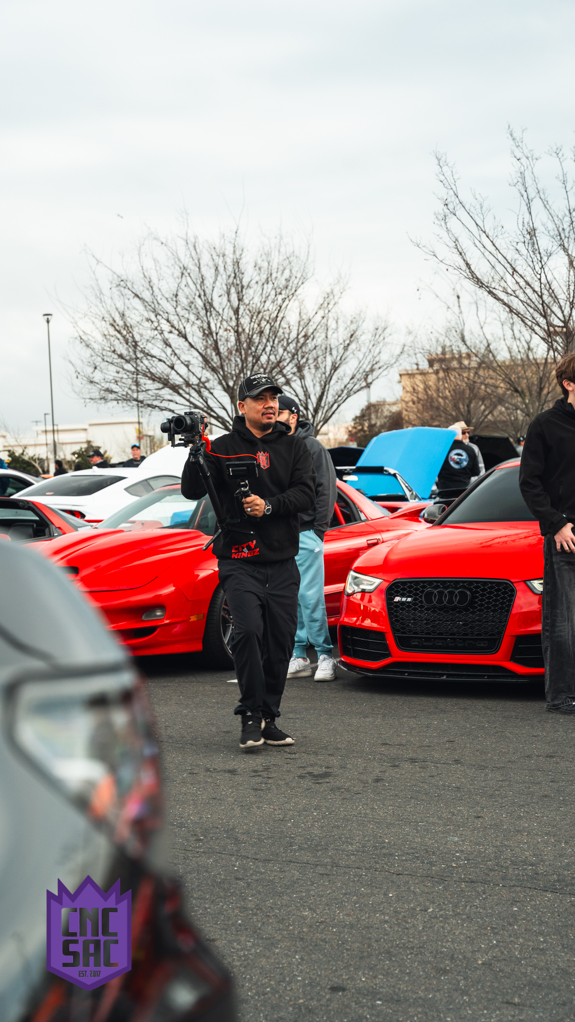 Attendees walking between parked cars at a Cars and Coffee Sac event