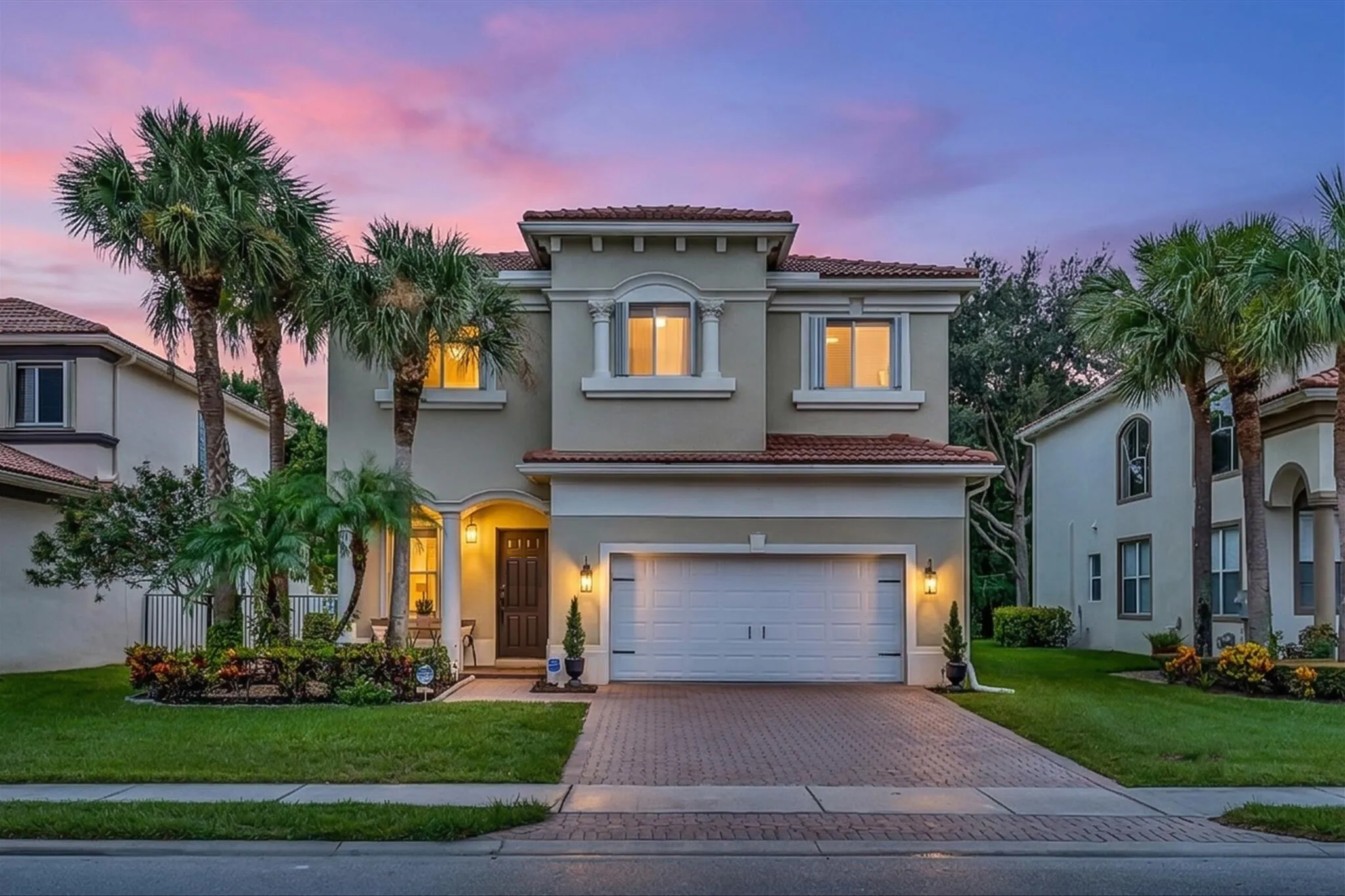 Elegant two-story stucco home with red barrel-tile roof and palm trees at twilight, Boynton Beach, Florida