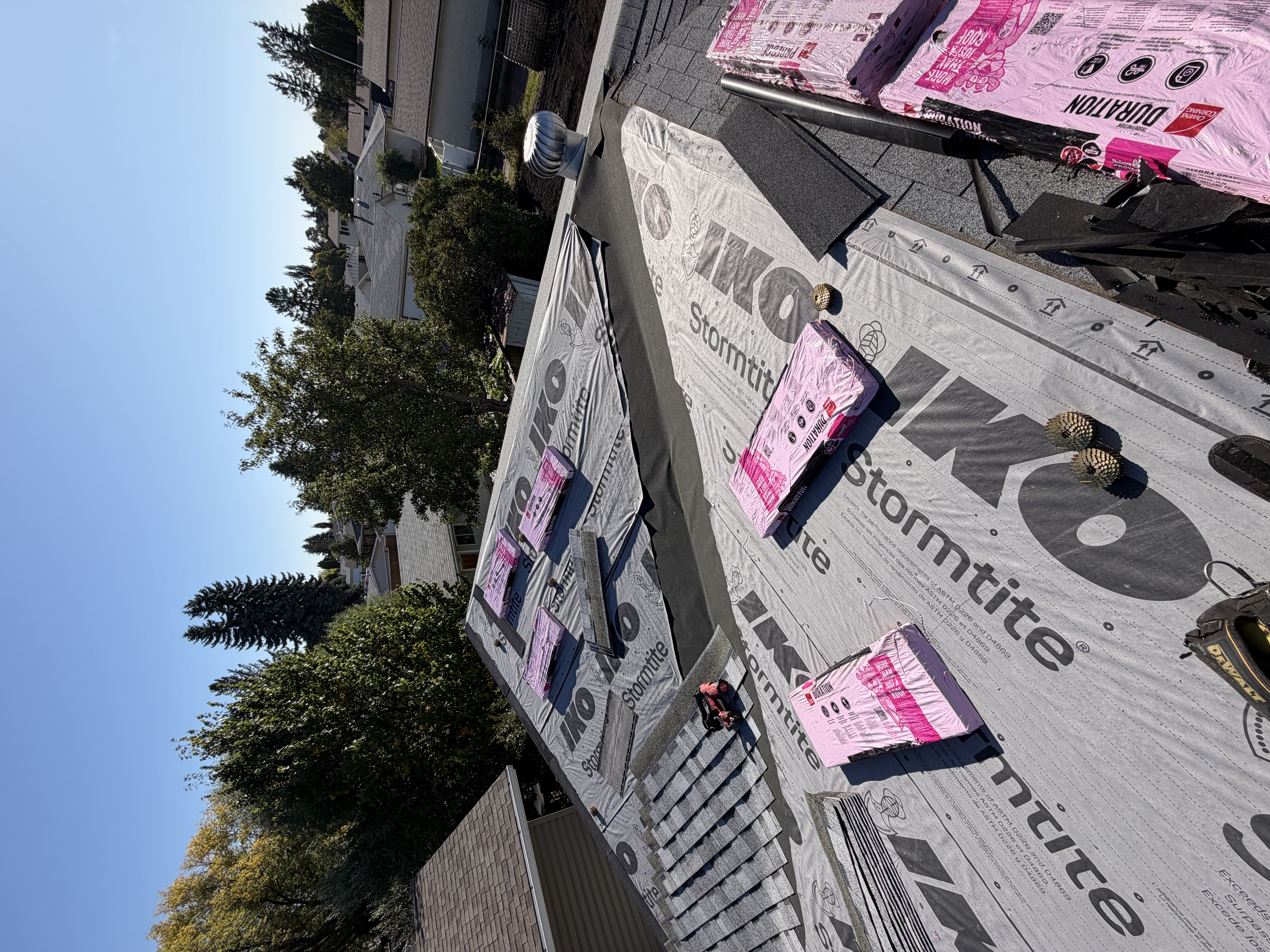 Underlayment and roofing material staged on a residential roof during replacement work