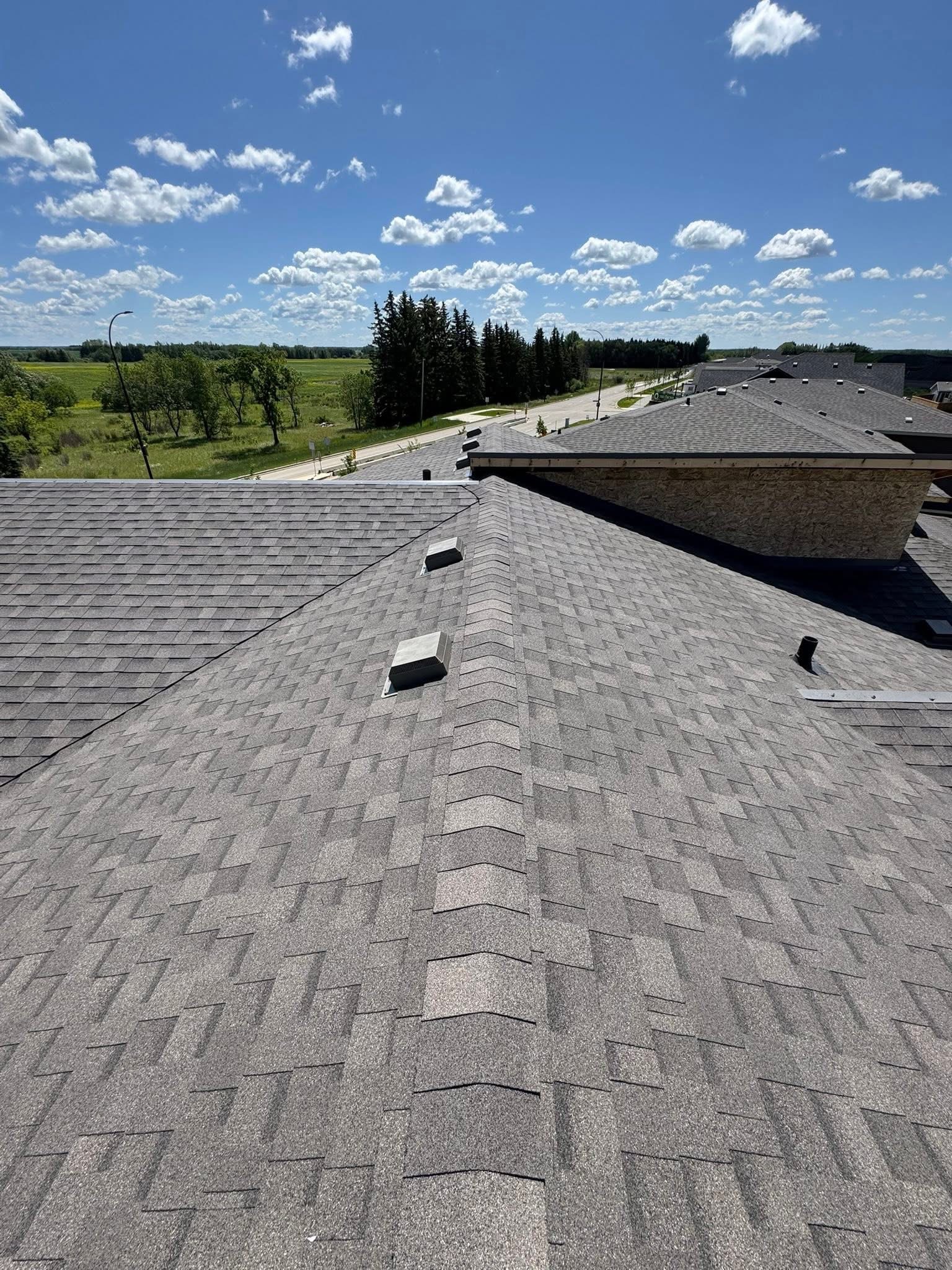 Residential roof with gray shingles under a blue sky
