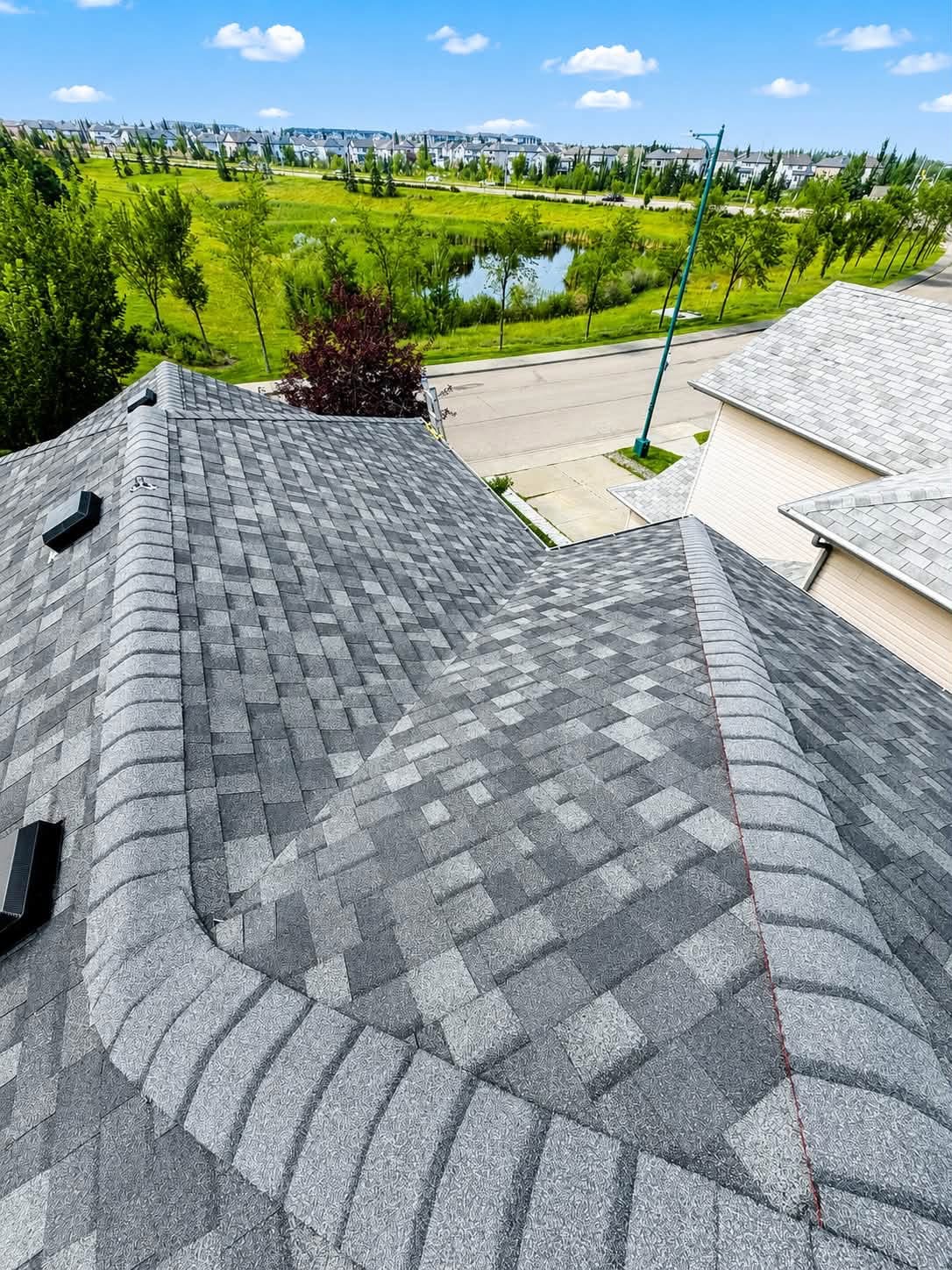 Residential roof with gray shingles and surrounding greenery