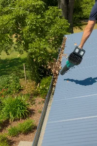 Gutter cleaner clearing leaves and debris from gutters with vacuum equipment