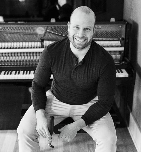 Picture of Brian Peerbolt with tuning instruments and sitting by a piano.