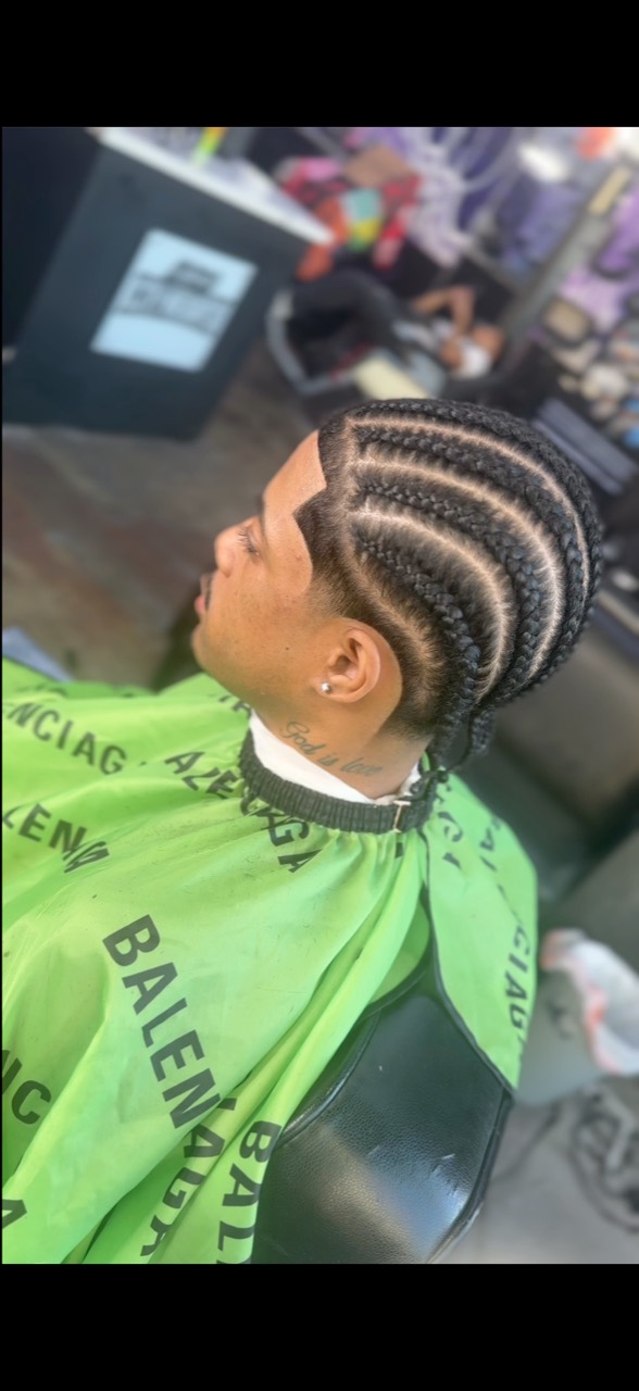 Side view of a client with curved cornrow rows and a shaped temple line.