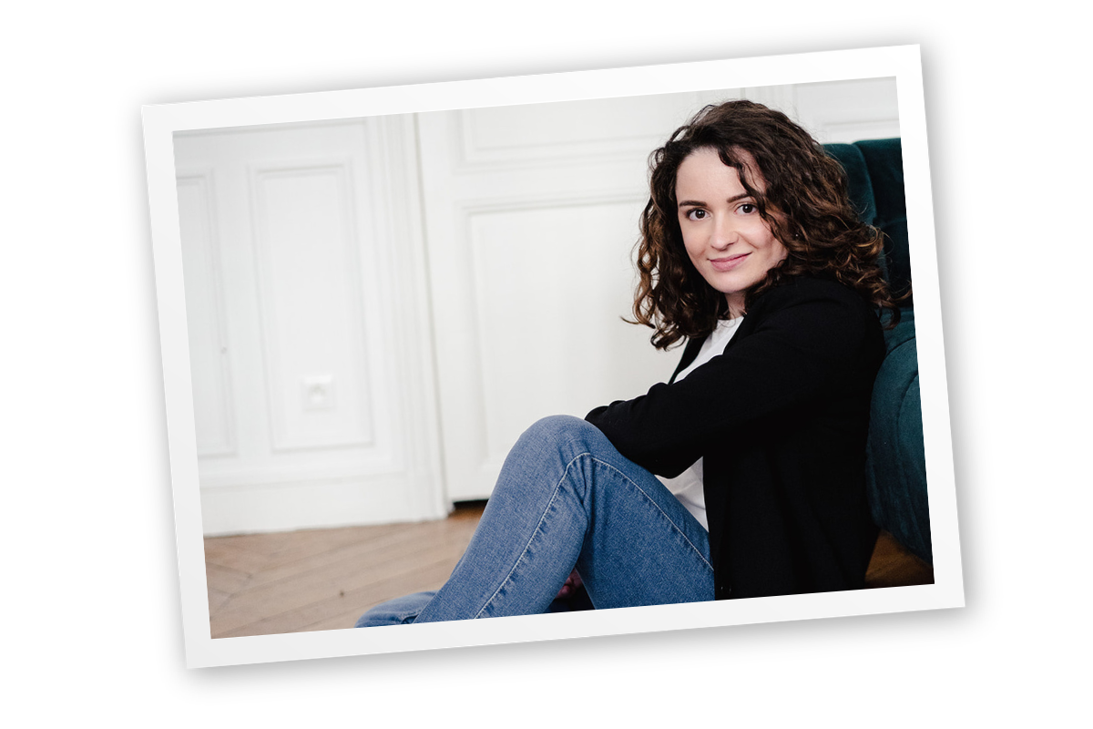 Marthe, assistante virtuelle, assise près d’un fauteuil, illustrant la réflexion face à un client difficile dans une relation professionnelle.