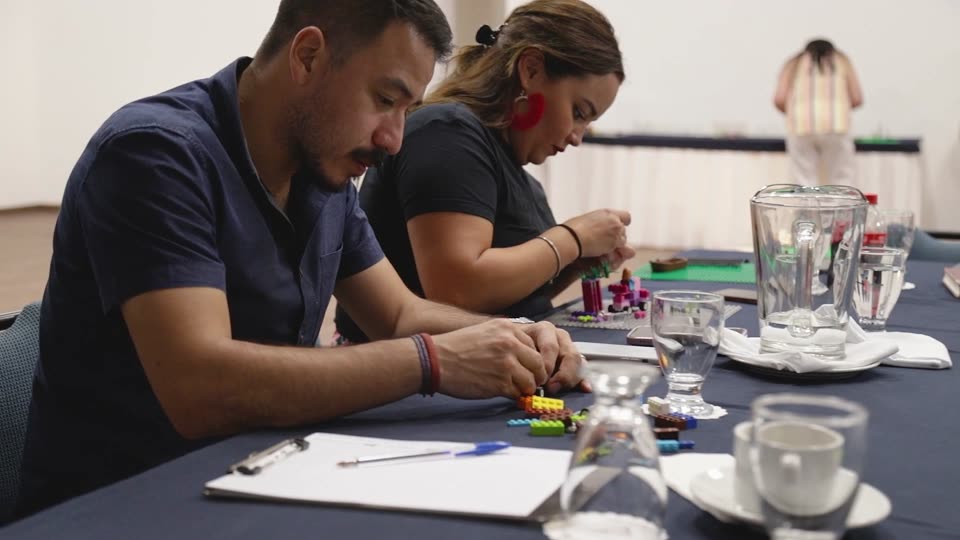 Una participante construye su modelo con piezas sobre una base verde
