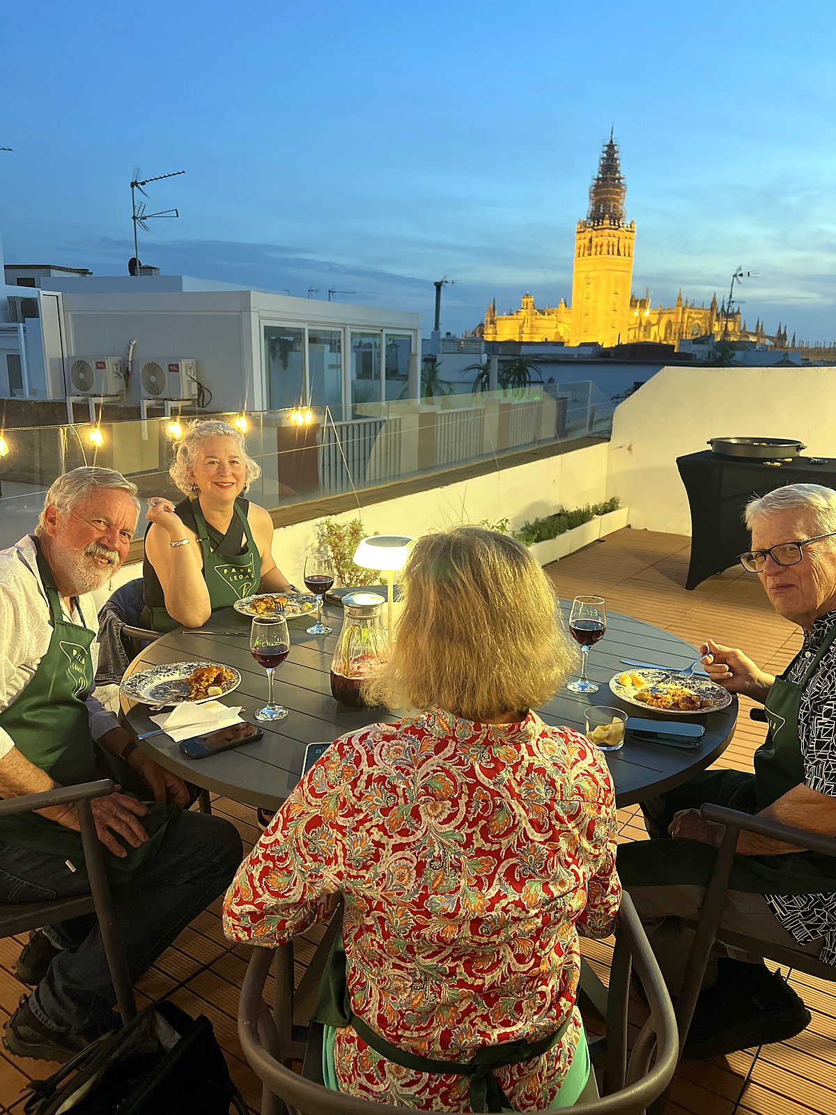Guests at dinner on the rooftop terrace at blue hour, the illuminated Giralda behind them