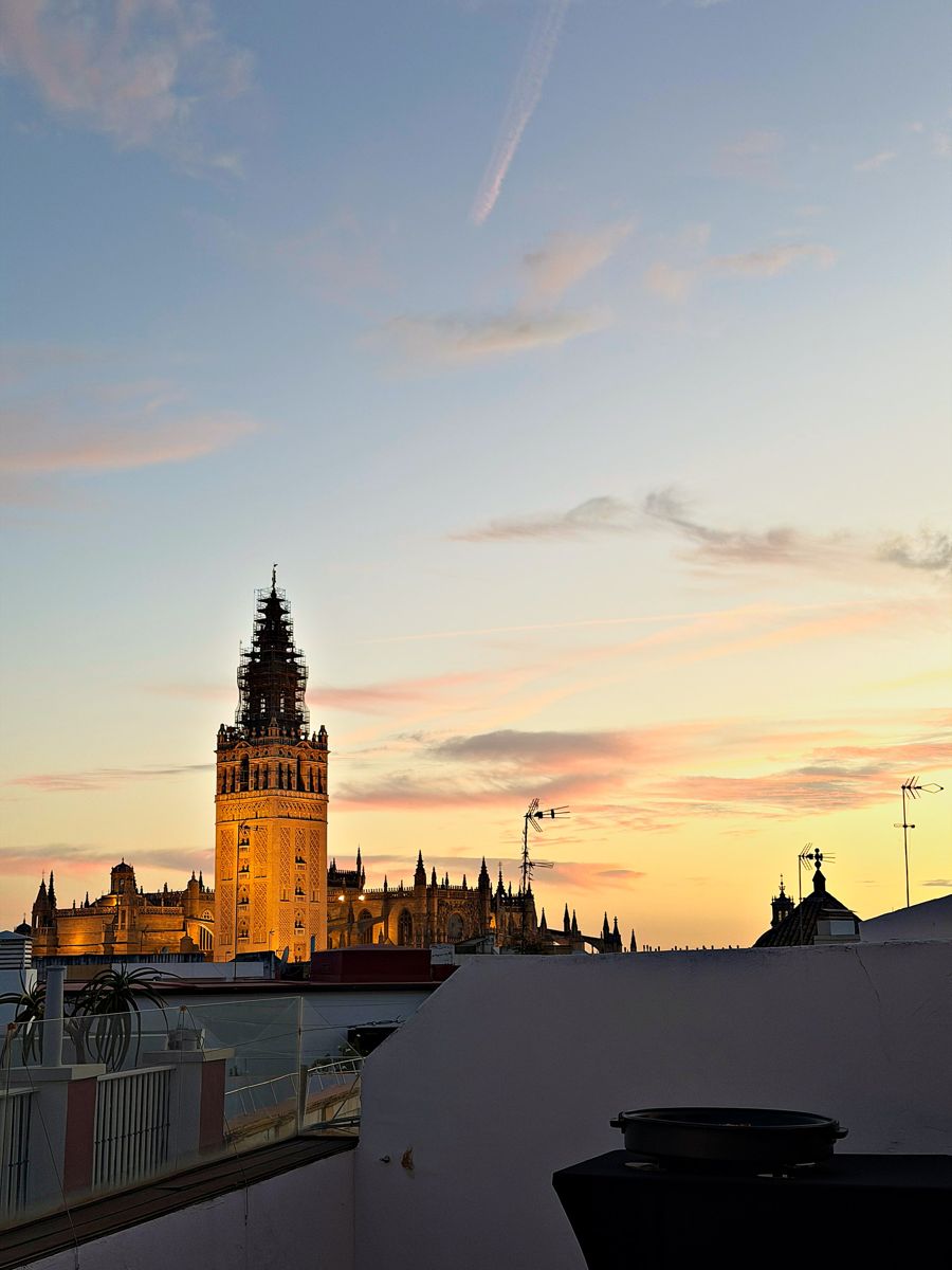 Golden evening light on the Giralda under a sunset sky, seen from a rooftop in Seville's old town